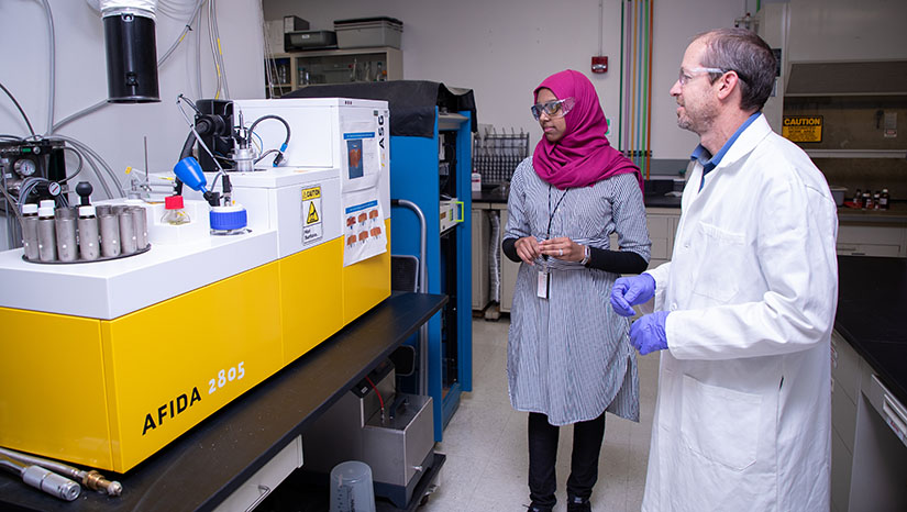 Two researchers looking at a fuel properties analysis machine.