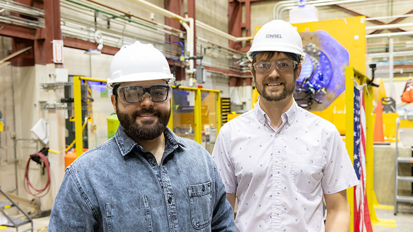 Two people wearing hardhats stand inside a lab