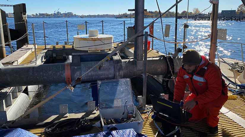 A researcher examining data on a boat with a turbine