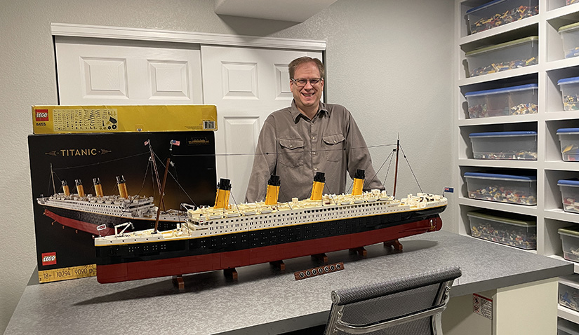 A man stands by a model ship. 