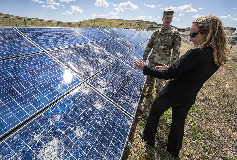 A woman and a military officer inspect a PV array. 