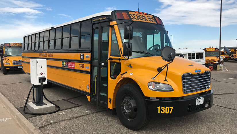 Electric school bus parked at a charging station.