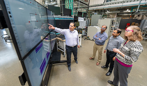 Four researchers in a laboratory review data on a large screen