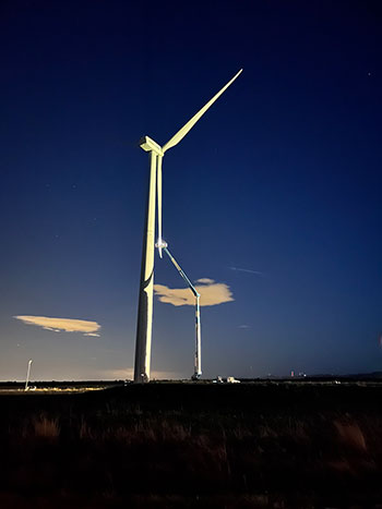 A worker in an extended aerial lift works on the blade of a wind turbine.