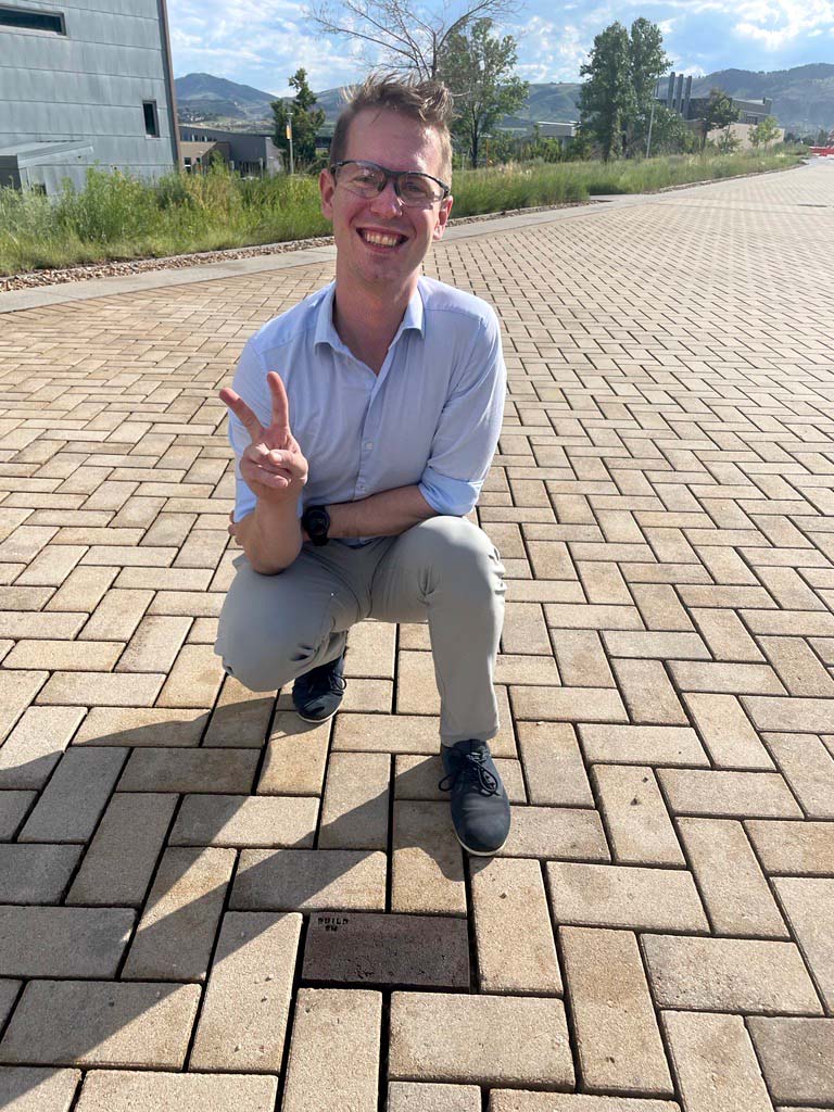 Male researcher crouching next to brick of concrete alternative