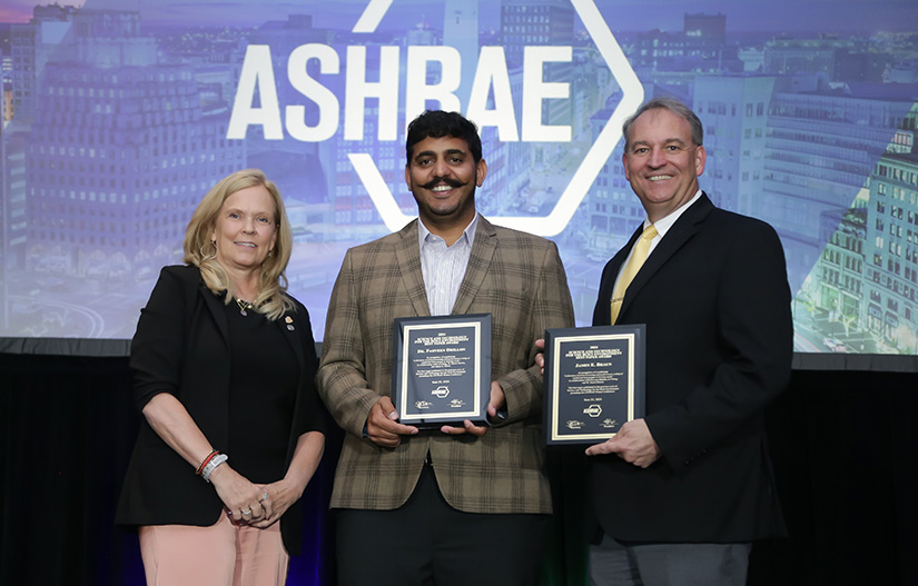 Three people holding an award onstage.