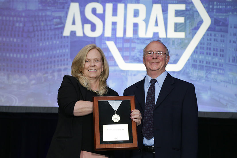 Two people holding an award onstage.