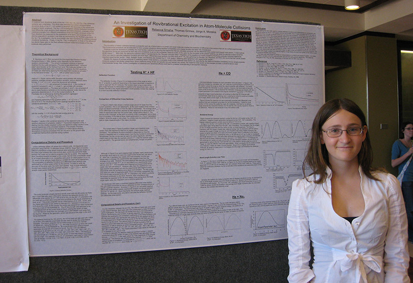 A student standing in front of a chemistry poster.