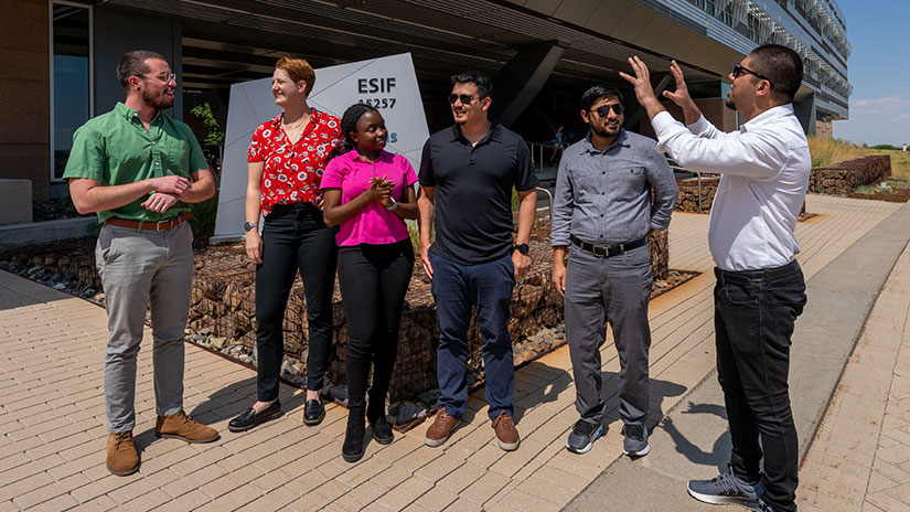 Group of interns stand outside building talking