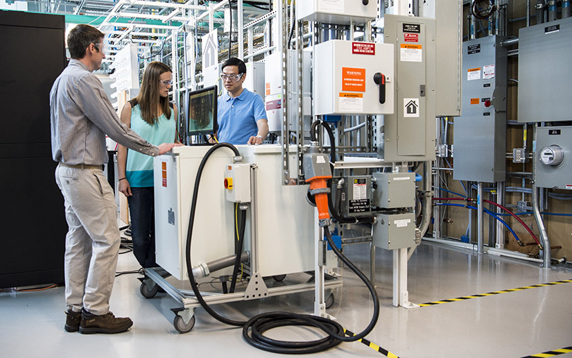 Three people looking at large lab equipment.