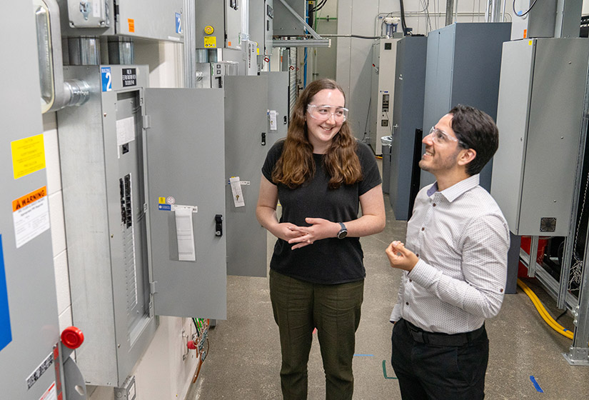 Two people looking at electrical panels.