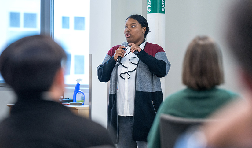 A woman holding a microphone while speaking to an audience.