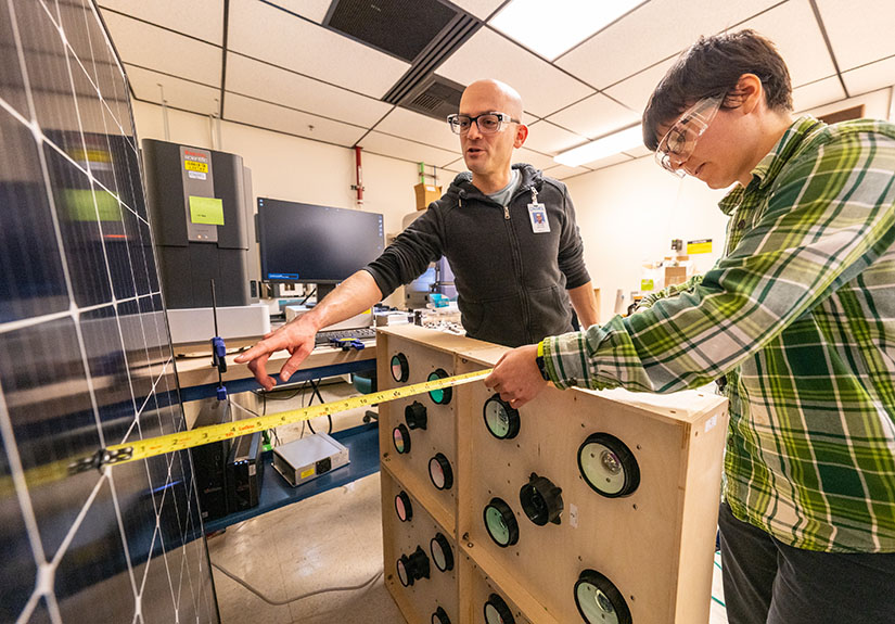 Two people work on a solar panel in a room.