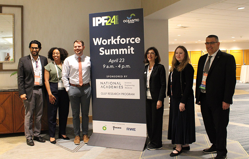 A photo of six people standing next to a sign for a workforce summit