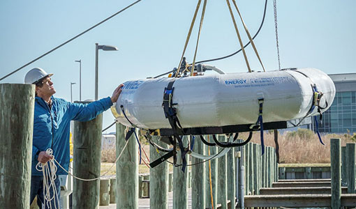 Person prepares marine energy device on dock for deployment