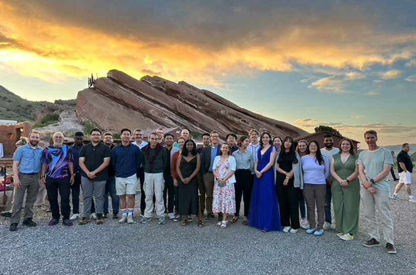 A group of people standing in front of a rock formation.