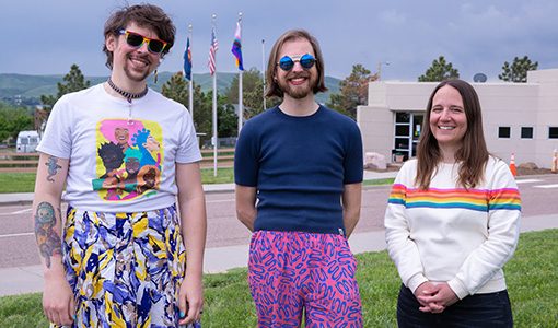 Three people standing in front of a flagpole. 