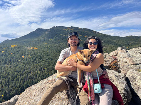 Paula Pérez, her boyfriend, and their dog sit on top of a mountain.