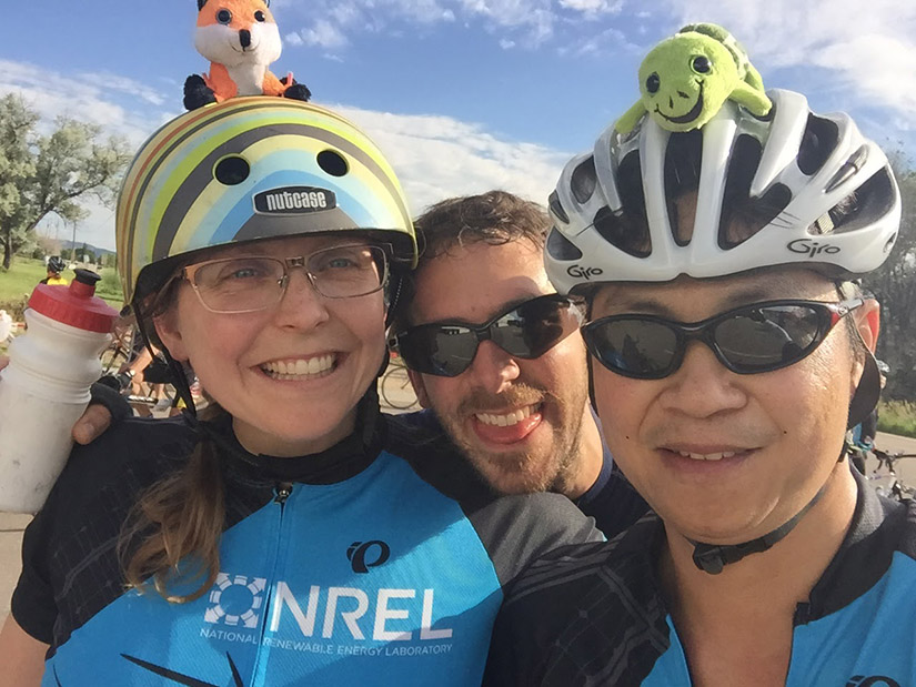 Three people wearing bike jerseys and helmets. 