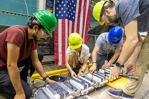 People work on a flexible wave energy converter device