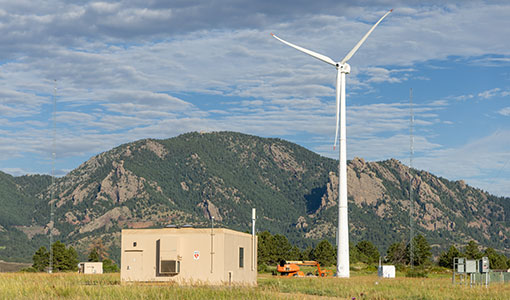 Wind turbine stands in a field next to an out building