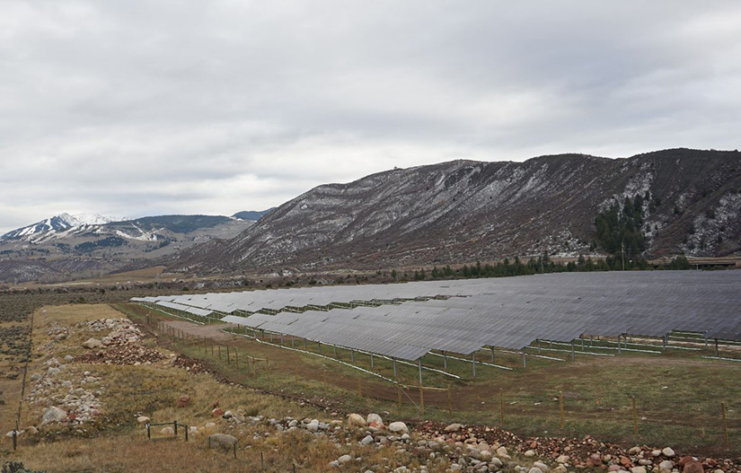 Rows of solar panels in front of a mountain. 