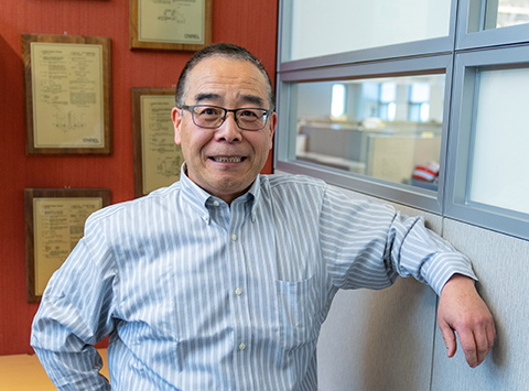 A smiling man poses in front of plaques on a wall.