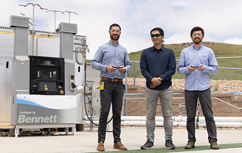 Shaun Onorato, Taichi Kuroki, and Jamie Kee hold their 2024 Hydrogen Program Annual Merit Review awards in front of the hydrogen fueling infrastructure at NREL’s Golden, Colorado campus.
