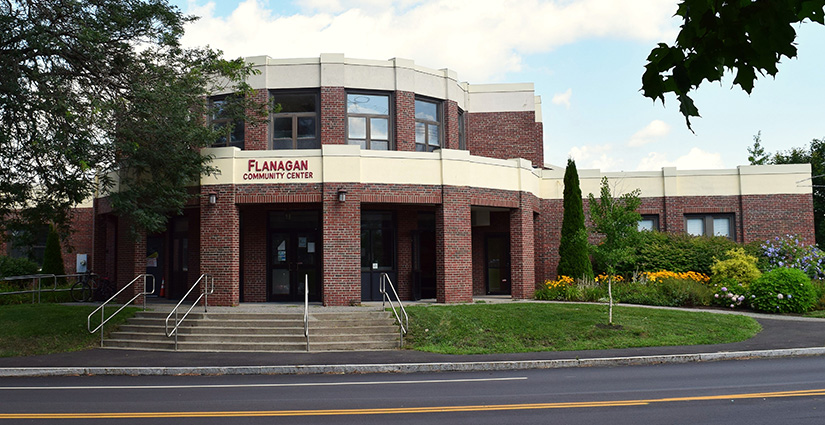 Brick building with green shrubbery and trees.