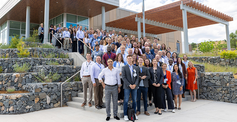 A group of 100+ people in business casual stand together on a stairwell outside.