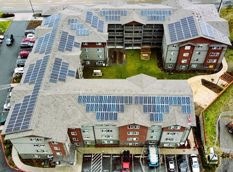 An aerial image of a large apartment building with solar panels on the roof.