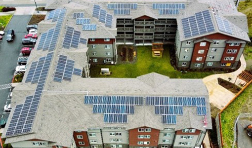 An aerial image of a large apartment building with solar panels on the roof.