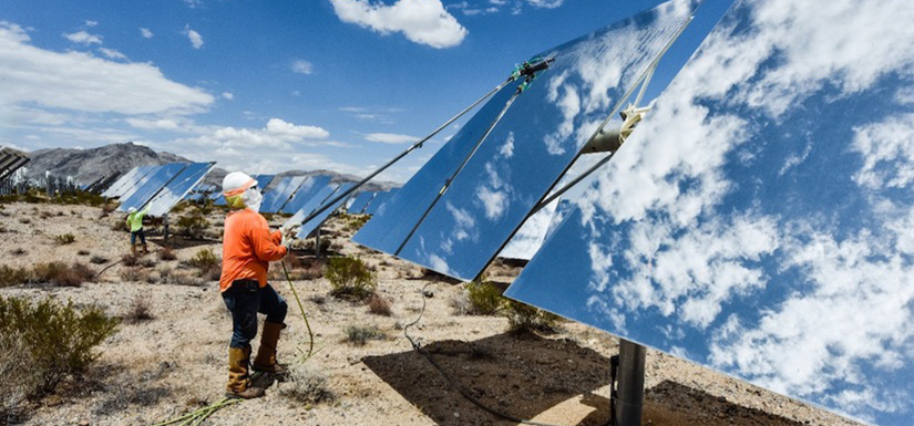 Two people cleaning multiple heliostats.