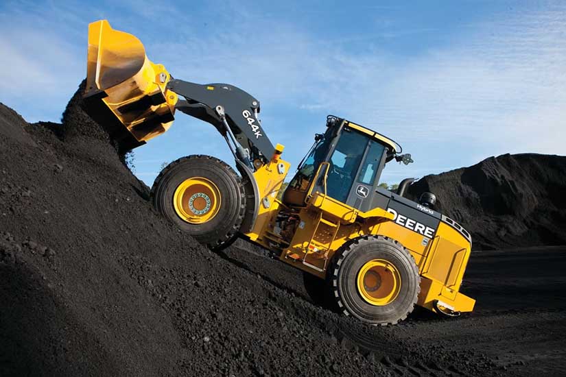 A John Deere heavy-duty 644 K hybrid loader climbs a steep dirt embankment. 