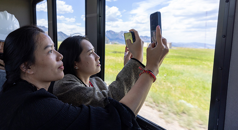 Two women holding phones toward a window.