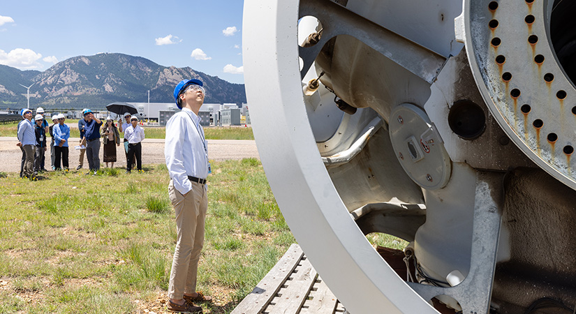 A man looking at a large piece of metal with a large group of people standing in the background.