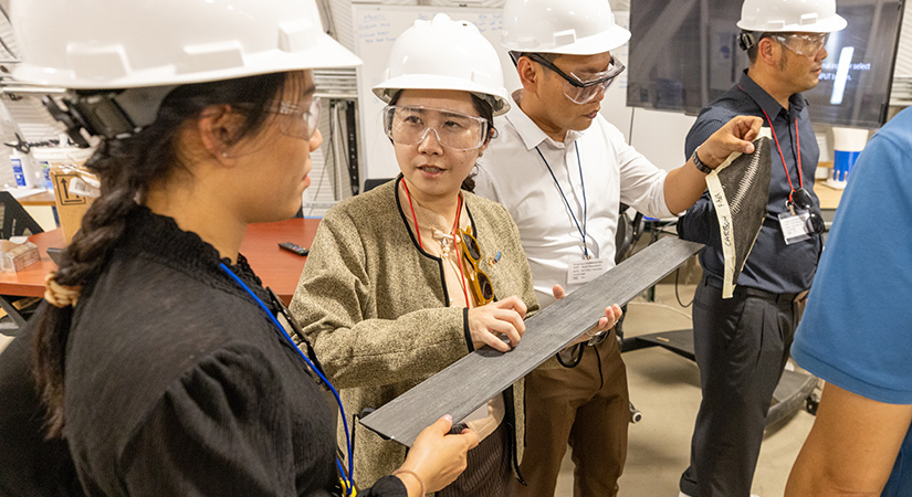 Four people examining a small piece of wood.