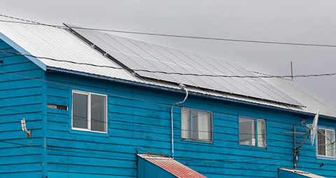 A blue house with solar panels on the roof.