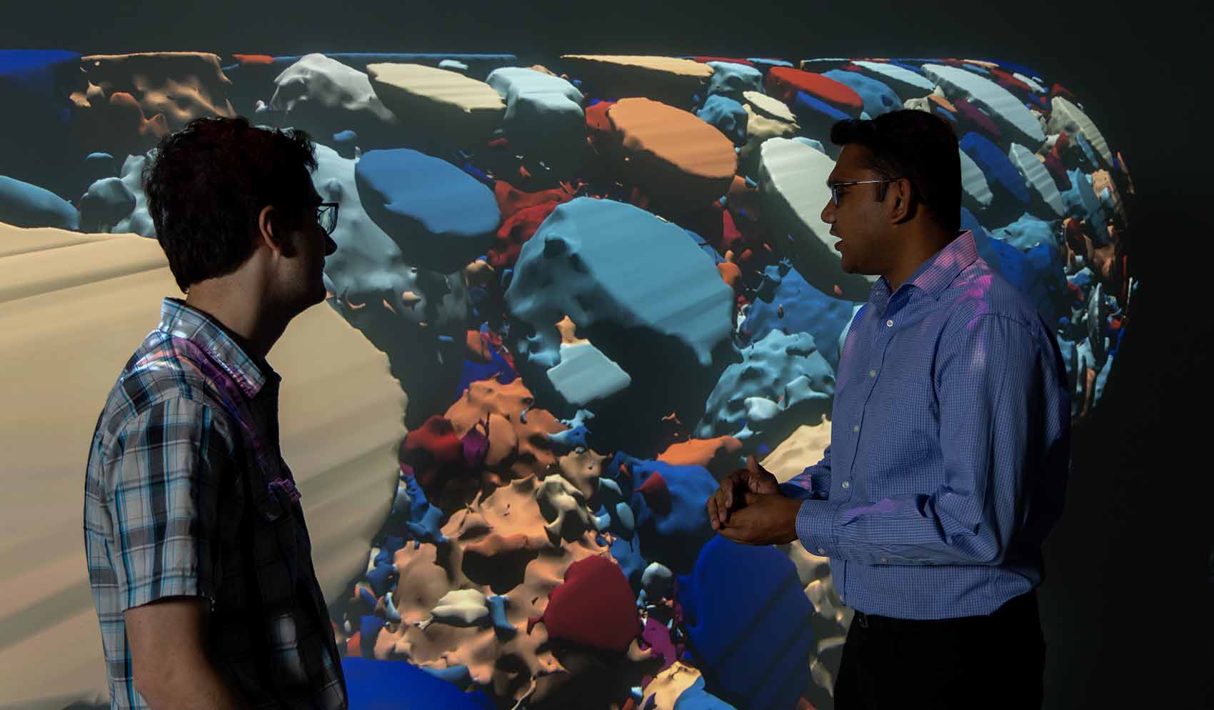 Two researchers in front of a wall projection.