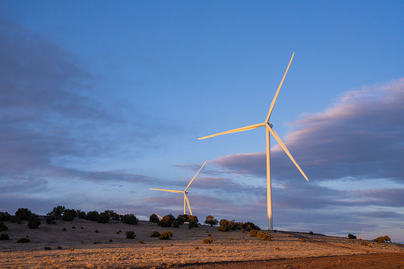 Two long-bladed wind turbines against a blue sky