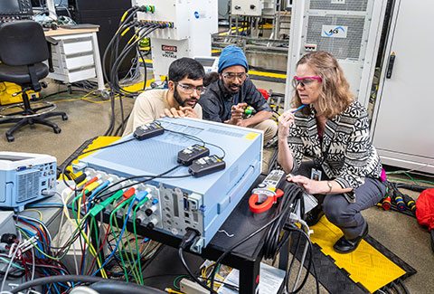 Three people performing lab test using ADMS test bed