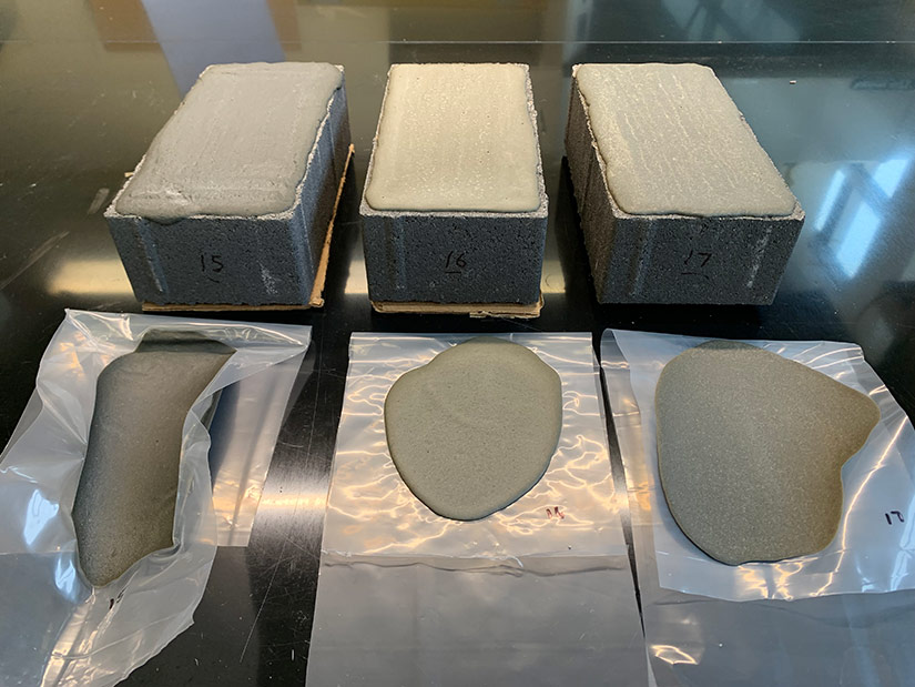 Three concrete bricks and three plastic casting sheets are each labeled with sample numbers and have liquid coatings applied on top of them.