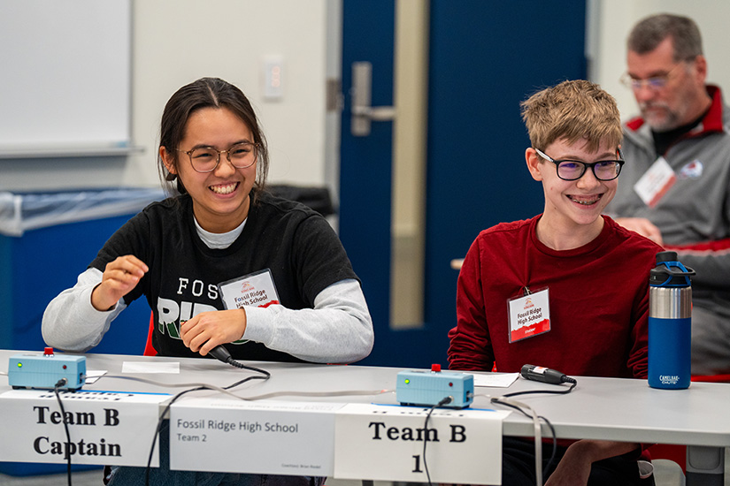 Two students sitting at a table smiling.