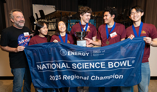 An adult and five teens hold up a fabric sign that reads National Science Bowl 2025 Regional Champion.