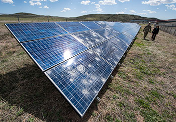 A military personnel walks alongside a solar panel array