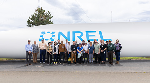 A group of people standing in front of a wind turbine blade.