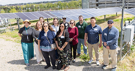 A group of people outside in front of solar panels.