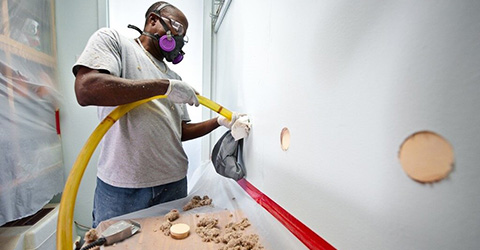 Person filling holes in wall with insulation.