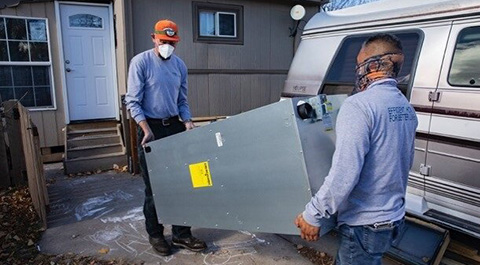 Two men carrying a large metal object.