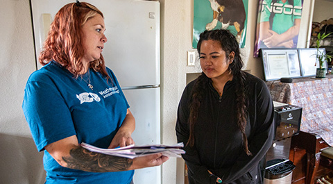 Two women looking at a stack of paper.